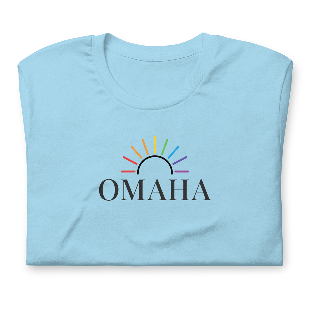 Rainbow sun arc over OMAHA typography. Center chest on soft unisex Bella + Canvas ocean blue cotton shirt. Close up.