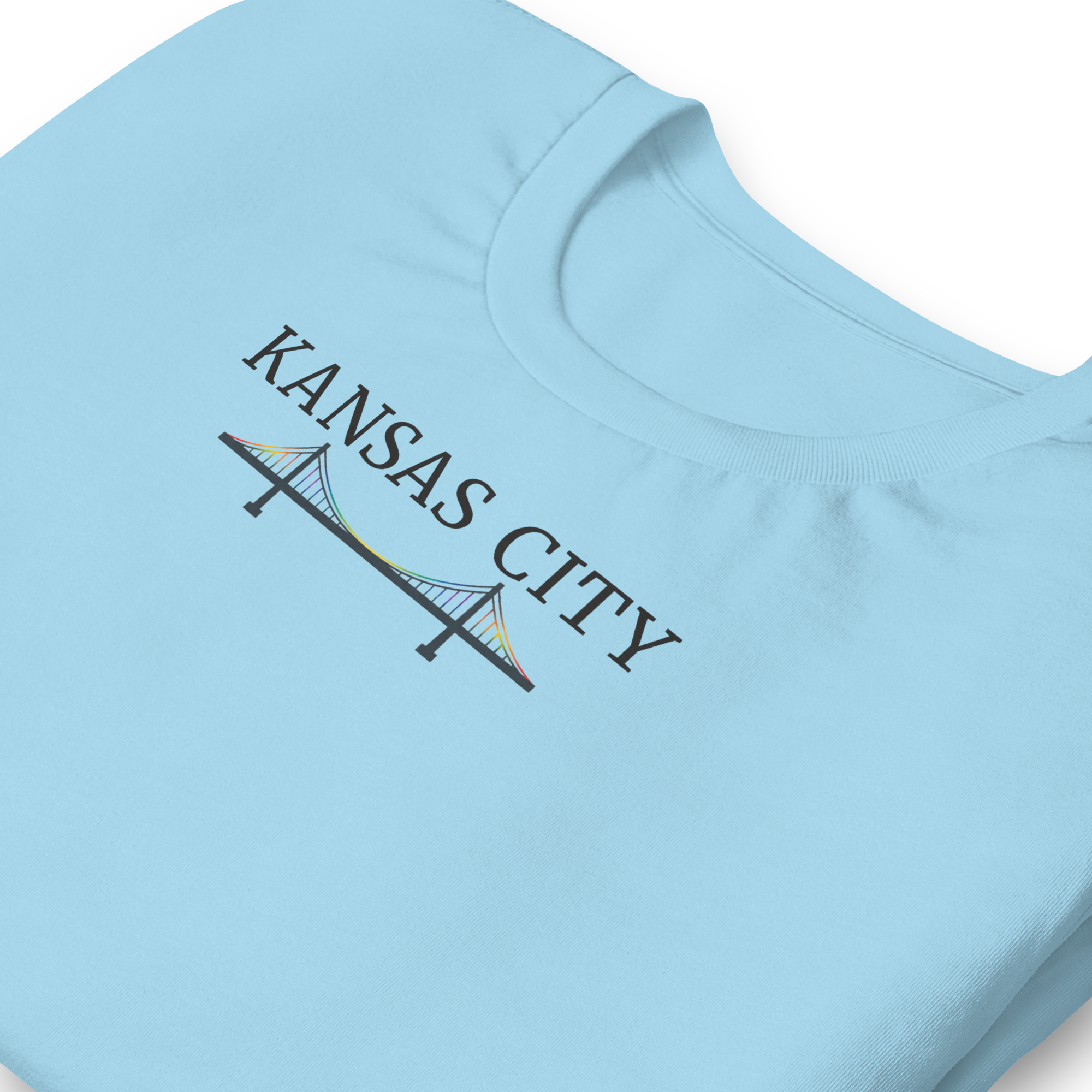 Kansas City typography above a rainbow bridge on unisex cotton Bella + Canvas shirt. Center chest ocean blue. Close up