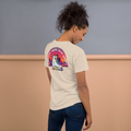 Person wearing beige shirt and jeans. Tshirt features a back print of Summer Nights Skate Party evening sunset and a skyline behind a rainbow roller skate. Printed on unisex Bella + Canvas cotton. 