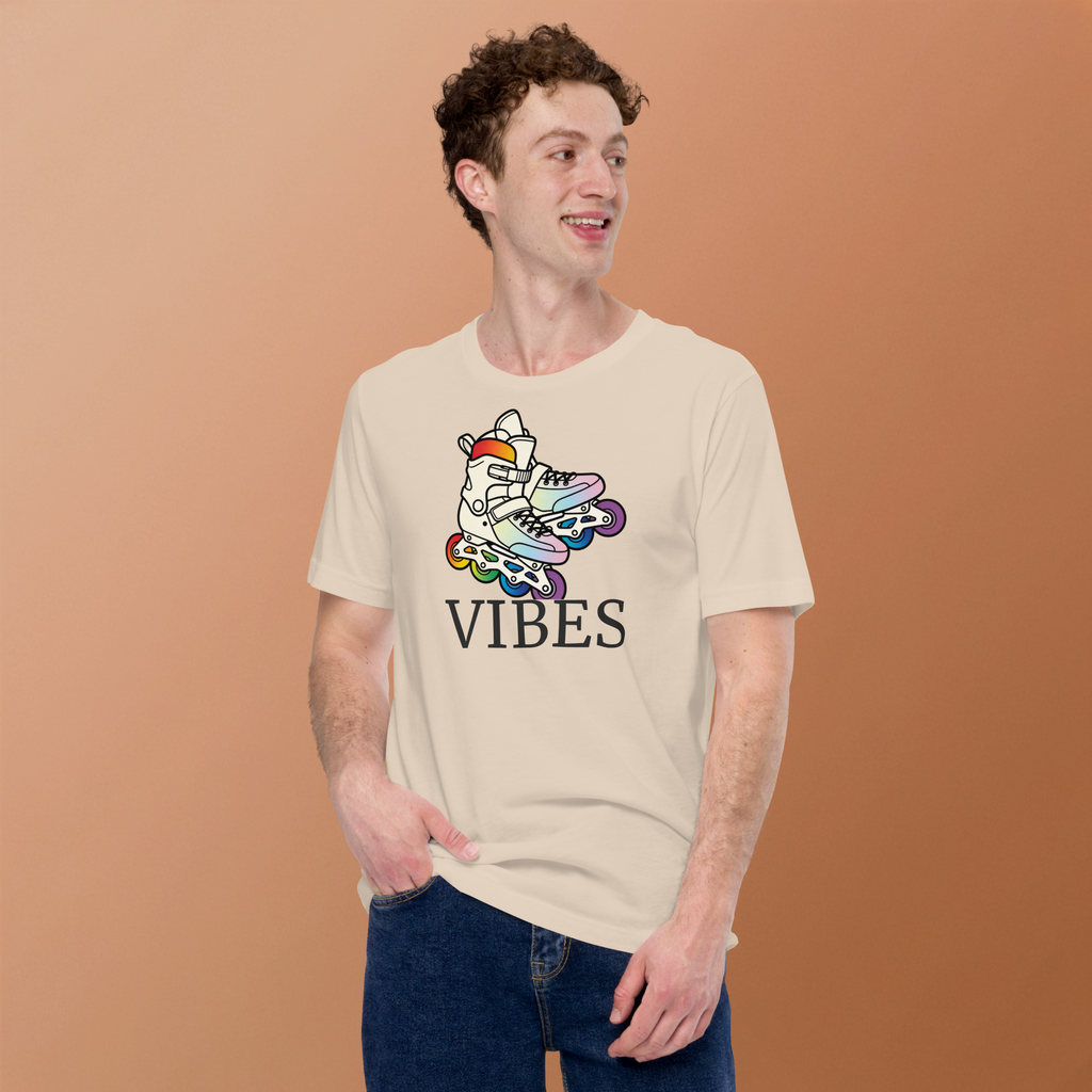 Model wearing  t-shirt of 2 inline skates in LGBTQ+ rainbow colors above VIBES text. Beige Bella + Canvas Cotton. Paired with jeans.