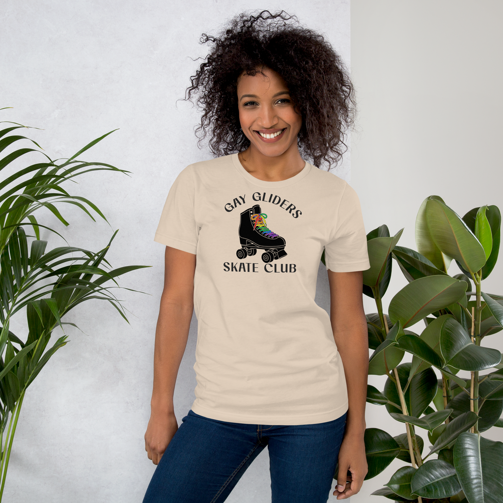 Model wearing badge style Gay Gliders Skate Club. Classic Black  roller skate with LGBTQ+ rainbow laces. Unisex beige Bella + Canvas cotton tee.