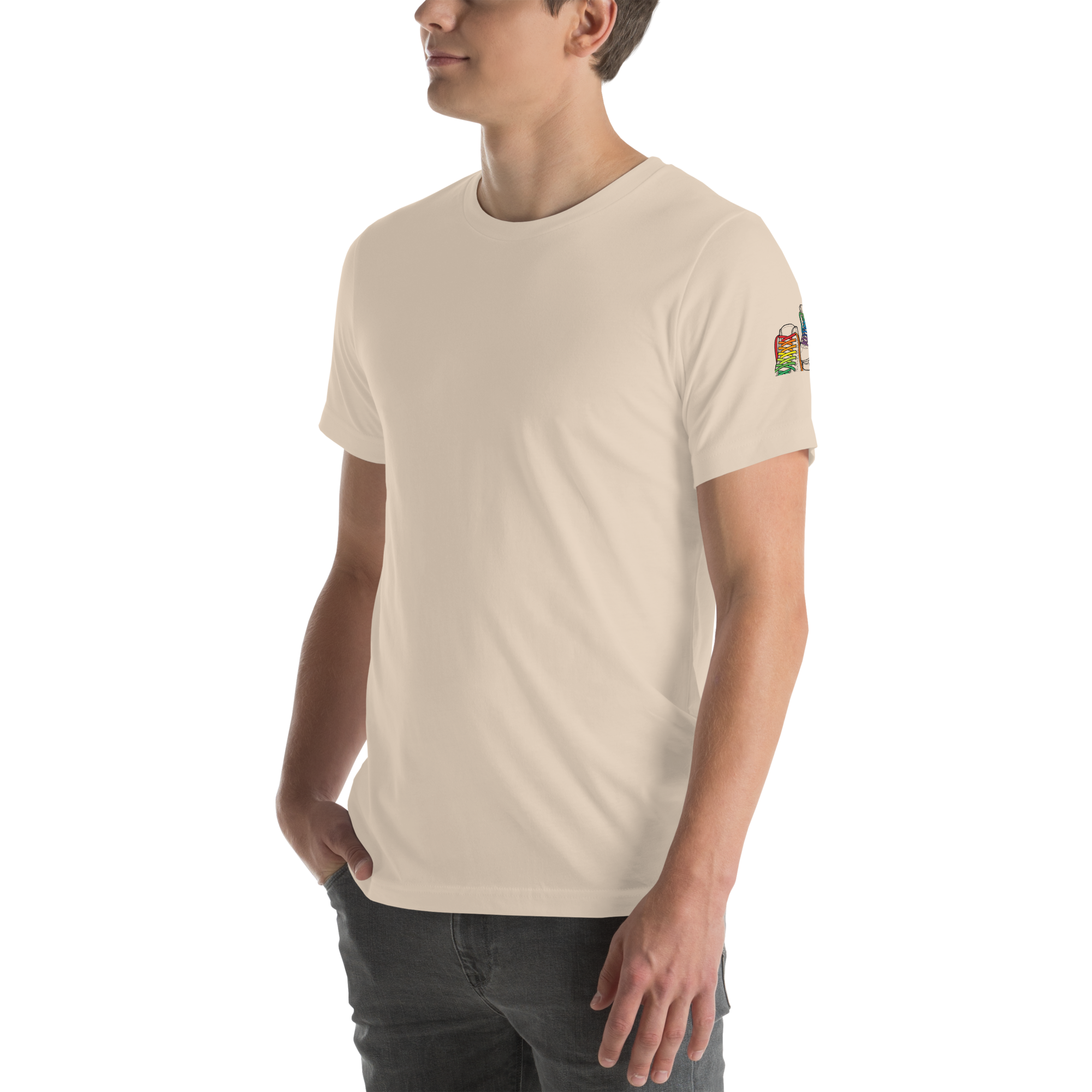 Model wearing beige shirt with outline of 2 quad skates with LGBTQ+ rainbow laces. Printed on left sleeve paired with jeans. Bella + canvas unisex cotton